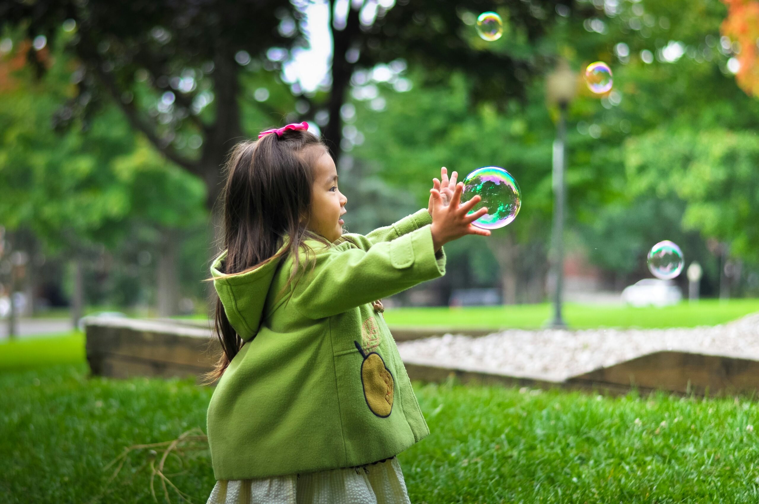 young child in a green coat playing with bubbles | centerforrisingminds.org