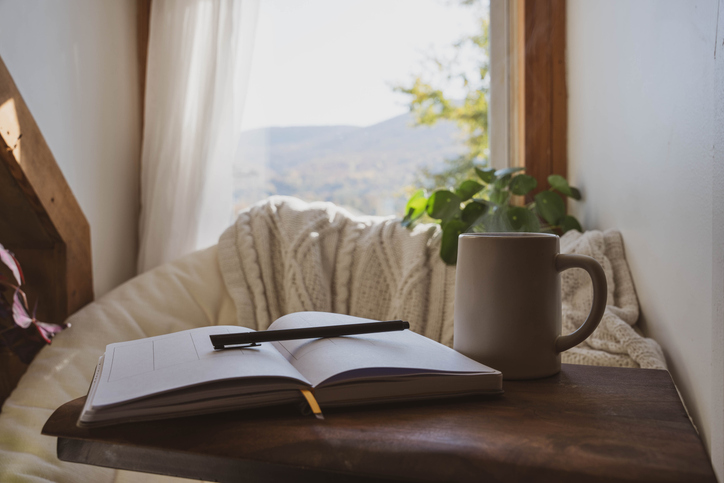 A cozy winter scene with a desk, mug, and open journal, symbolizing rest and reflection during end-of-year burnout.