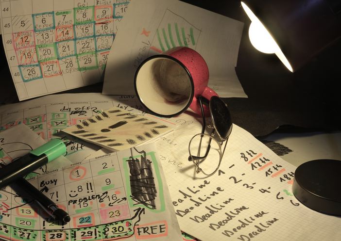 Cluttered desk with messy calendars, sticky notes, and papers representing planning fatigue and executive function overload.